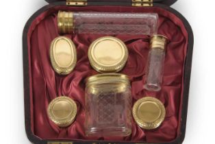 An Asprey & Co cased set of silver-gilt topped and engraved glass bottles and jars, hallmarked for