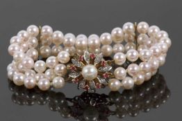 An 18ct cultured pearl, ruby and diamond bracelet, the three rows of round cultured pearls, each