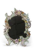 A continental porcelain mirror the porcelain frame with Rococo decoration with applied flowers and