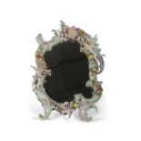 A continental porcelain mirror the porcelain frame with Rococo decoration with applied flowers and