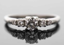 A diamond ring, the central round brilliant cut diamond with a smaller round brilliant and a