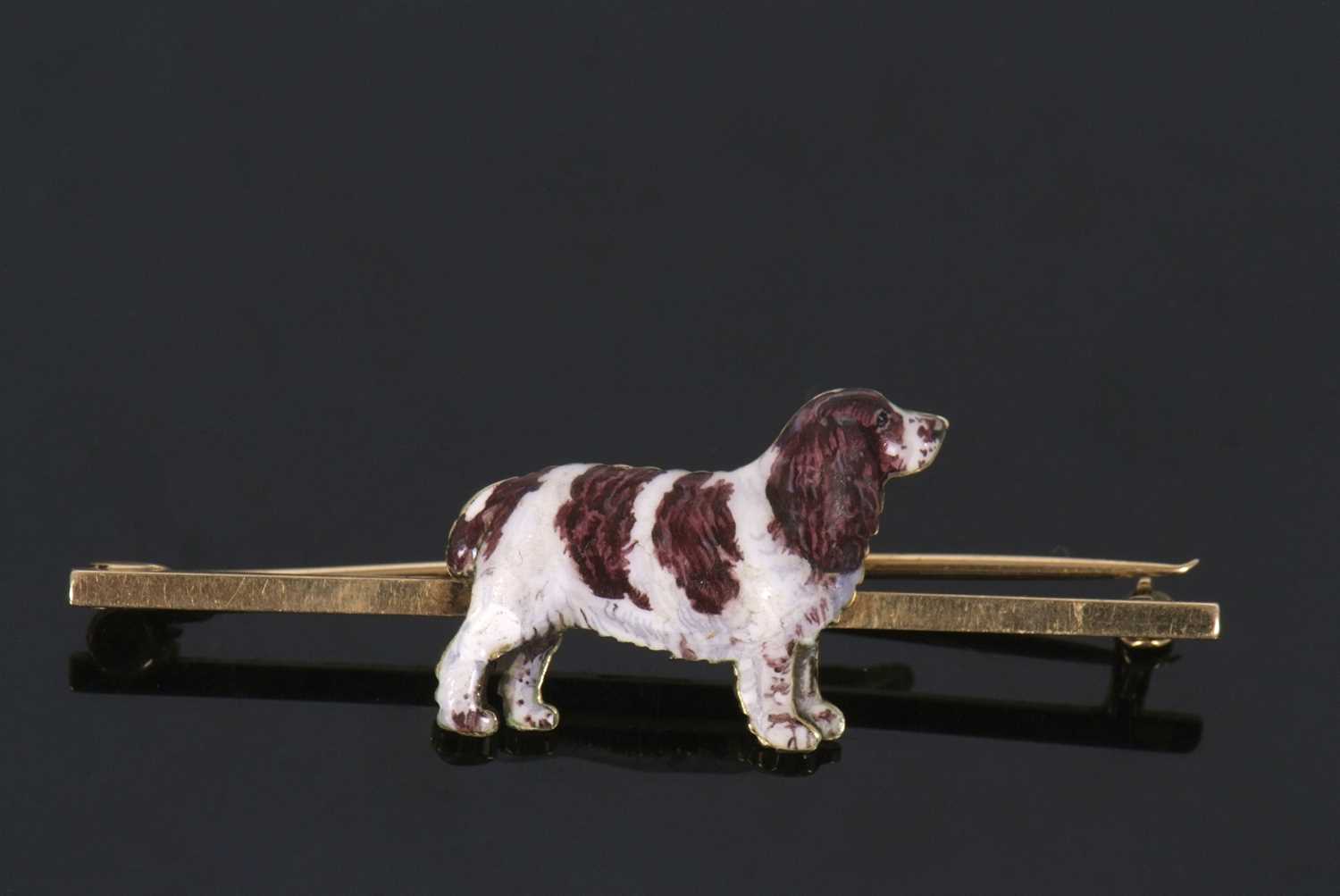 A 15ct enamelled spaniel bar brooch, the naturalistically enamelled spaniel set to a plain bar