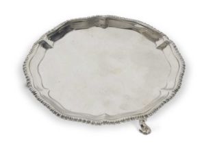 George III silver card tray having a shaped gadrooned border supported on three hoof feet,