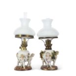 A pair of continental porcelain lamps with white frosted shades, the lamps decorated in the