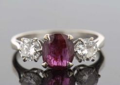An 18ct white gold ruby and diamond ring, the central off-round ruby in a four claw mount, set to