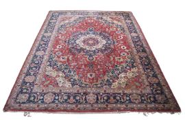 A large 20th Century Middle Eastern wool floor rug decorated with a central red and blue lozenge