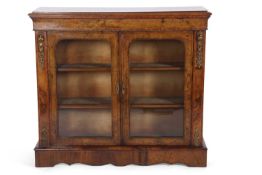 A Victorian walnut veneered bookcase cabinet with two glazed doors opening to a shelved interior set