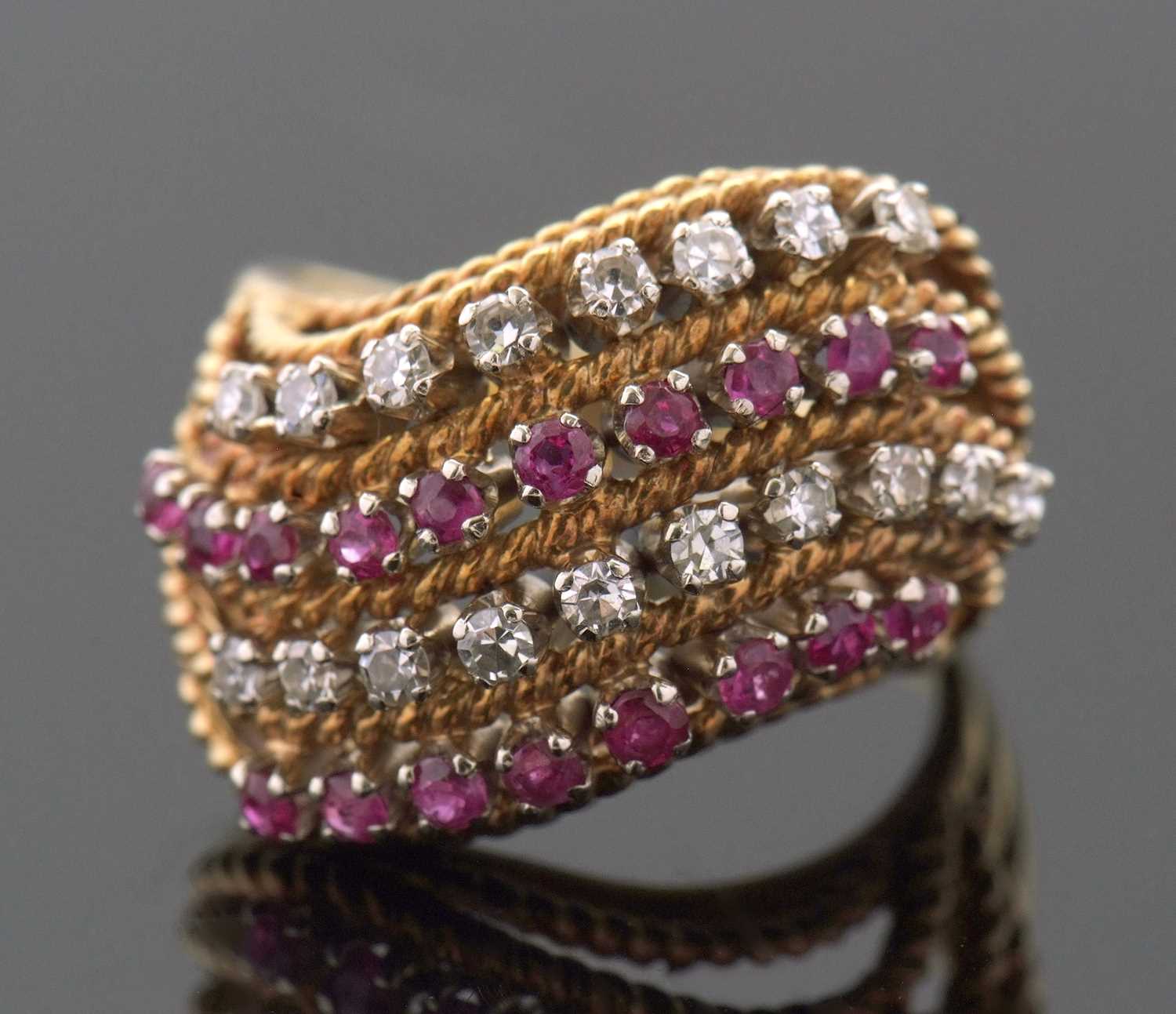 An 18ct diamond and ruby ring, set with four alternating curving diagonal rows of rubies and