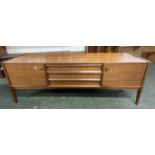 A mid Century teak sideboard with two end doors and three central drawers raised on tapering legs,