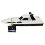 A large remote controlled speedboat with controller and on stand. Length approximately 96cm