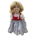 A reproduction German bisque head googly eye-eye doll, in patterned dress with blonde hair and