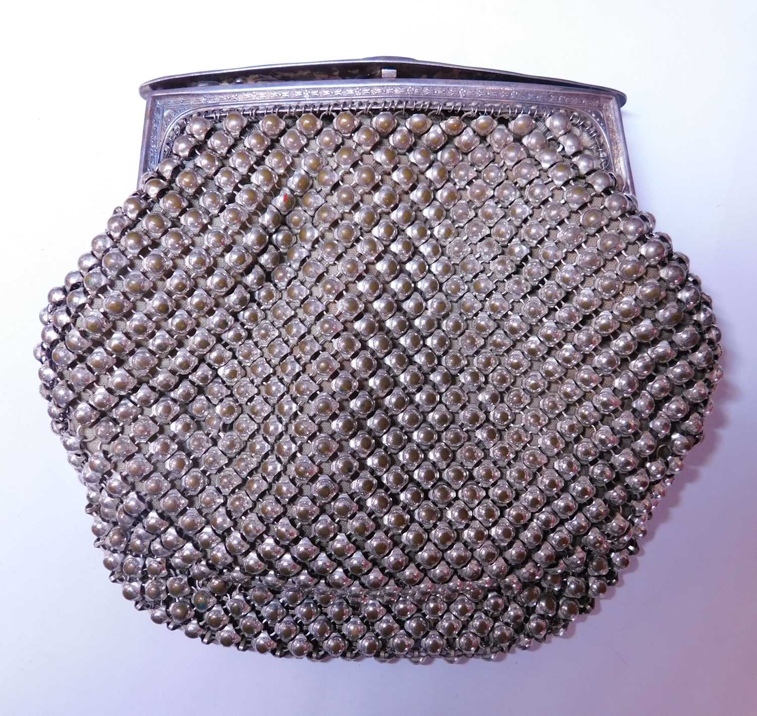 A lady's metal evening purse, with hinged fastener with engraved detailing to edges and ridged press