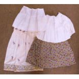 Four mid-20th century skirts, to include a floral patterned skirt, a cream cotton skirt with