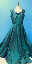 An emerald green satin evening gown with velvet and sequin trim, wide shoulder straps and full skirt