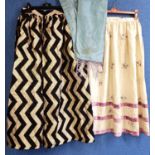 Two skirts, one a custom made black and gold zigzag patterned skirt and a cream silk embroidered