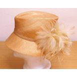A straw hat by Failsworth Millinery, in biscuit colour with feather and bead detail