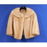 A lady's blonde mink bolero with three quarter sleeves and deep round neck collar with fur covered