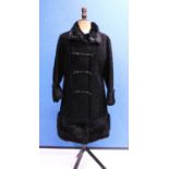 A black astrakhan coat by Astra Furs, Paris, the double breasted coat, with braided and button