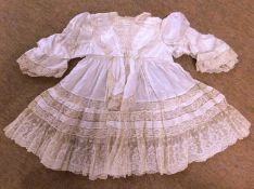 A late 19th/early 20th century childs cream silk and lace dress, with round neck, gathered waist and