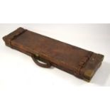 A leather-bound wooden Holland & Holland fitted single gun case with brass edges on corners, paper