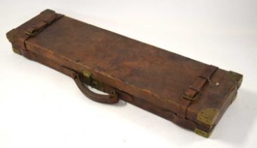 A leather-bound wooden Holland & Holland fitted single gun case with brass edges on corners, paper
