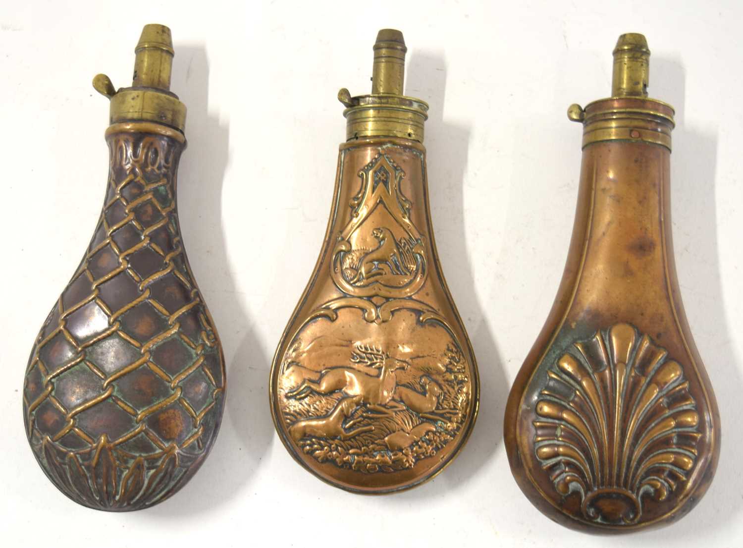 Three 19th century brass and copper powder flasks to include copper powder flask with dogs and a
