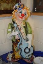 A large pottery model of a guitar playing clown