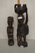 A tribal hardwood carved standing figure carrying an elephant together with another (2)