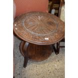 An early 20th Century oak circular two tier occasional table with carved decoration