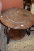 An early 20th Century oak circular two tier occasional table with carved decoration