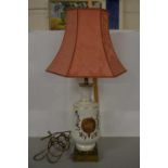 A cream and gilt glazed table lamp with peach damask shade