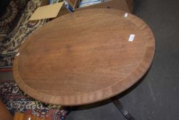 An oval coffee table with tripod legs and claw feet