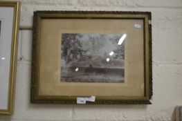A framed sepia photograph of figures by a riverside