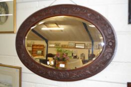An oval bevelled wall mirror with carved frame