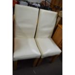 A pair of cream leatherette dining chairs