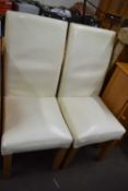 A pair of cream leatherette dining chairs