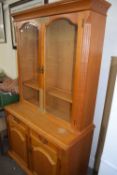 A pine cabinet with glazed doors above, cupboards and drawers below