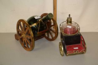 A retro cognac bottle mounted on a gun carriage type stand together with a further bottle on wheeled