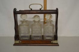 An oak and brass mounted tantalus, no keys present, unnamed, bottles chipped