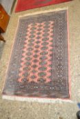 Small modern floor rug with geometric design on a pink background