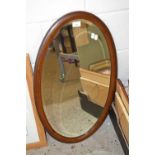 An Edwardian oval bevelled wall mirror in hardwood frame