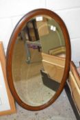An Edwardian oval bevelled wall mirror in hardwood frame