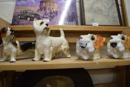 A pair of novelty dog mugs together with a figure of a Highland Terrier and one of a Bassett
