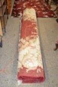 A large 20th Century red ground wool floor rug with floral decoration