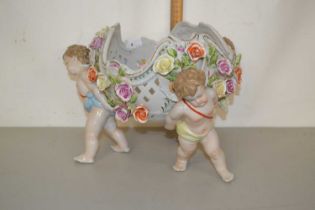 A 20th Century continental porcelain centre piece vase with cherub formed legs