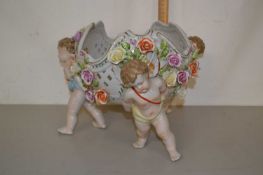 A 20th Century continental porcelain centre piece vase with cherub formed legs