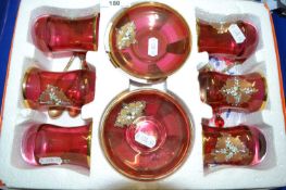A case of gilt finish ruby glass cups, saucers and accompanying spoons