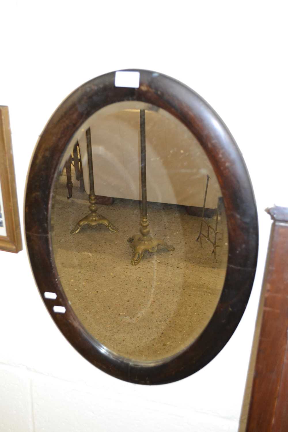 An oval bevelled wall mirror in hardwood frame