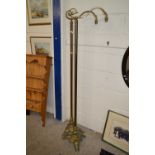 A pair of early 20th Century brass standard lamps raised on three footed bases