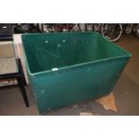 A plywood and green plastic laundry bin on casters